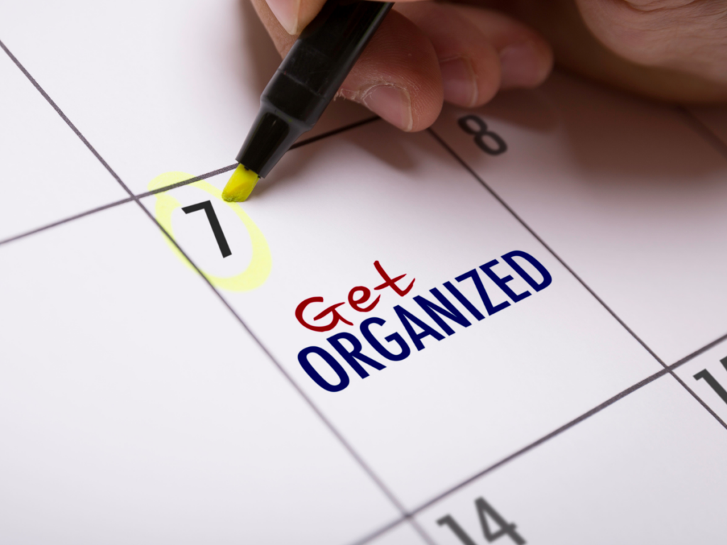 A person writing the word get organized on a calendar to avoid organizing mistakes of procrastination.